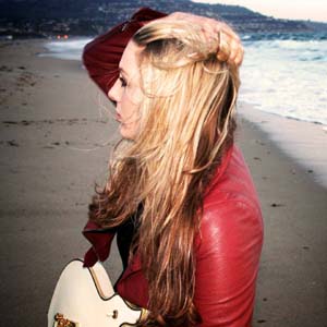 Stephanie Pickard on beach with guitar